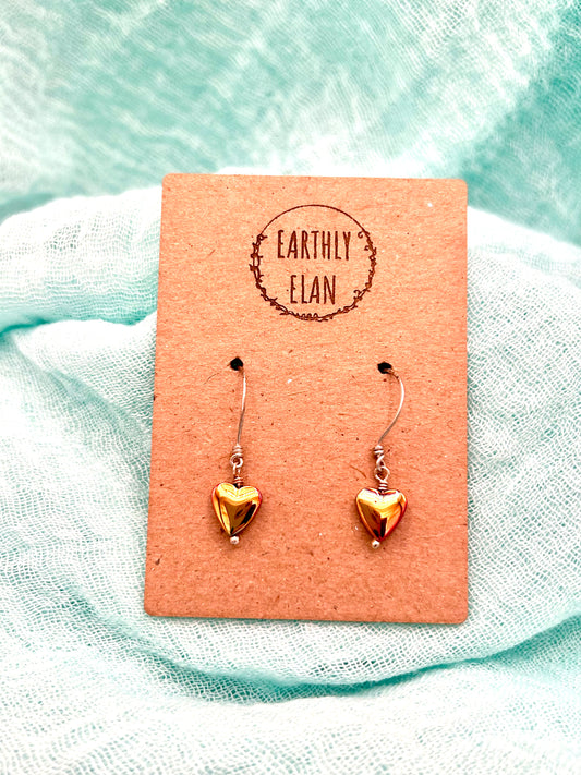 Iridescent hematite heart shaped drop earrings on a brown card